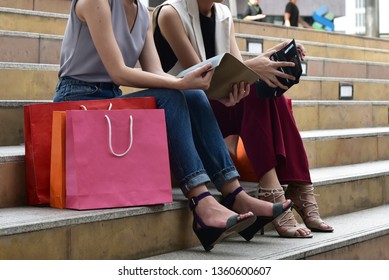 Shopping  concept  :  Two women sit down together on the stair with colorful shopping bag 