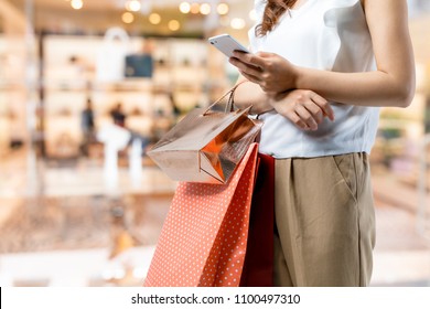 shopping concept. woman using smart phone with shopping bag. - Shutterstock ID 1100497310