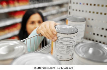 Shopping, Consumerism And People Concept - Woman Taking Tincan With Food From Shelf At Grocery