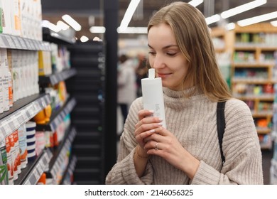 Shopping cosmetics - woman smelling bottle of shampoo in store. - Shutterstock ID 2146056325