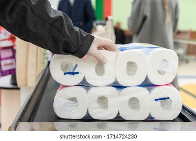 Shopping During Virus Outbreak. Man Customer In Protective Rubber Gloves Putting Toilet Paper Packaging On Checkout Counter Conveyor Belt. Grocery Store, Supermarket. Pandemic. Coronavirus. 