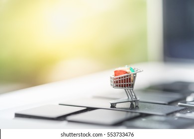 Shopping and e-commerce concept. Close up of miniature shopping cart toy figure on laptop computer