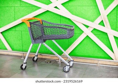 shopping empty plastic trolley against the background of a green wall in a shopping center. Shopping for the week - Powered by Shutterstock