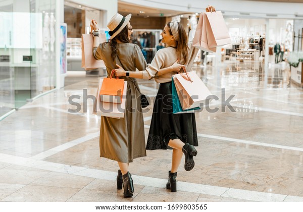 Shopping and entertainment, mall inside. Two\
beautiful girls with paper bags at the mall. The joy of\
consumption, Gift shopping,\
holiday