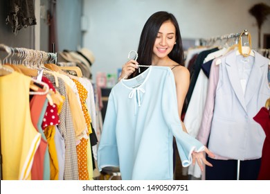 shopping, fashion, style and people concept - happy woman choosing clothes and looking to mirror in mall or clothing store - Powered by Shutterstock