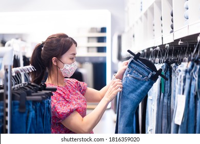 Shopping, Fashion, Style And People During Covid19 - Happy Woman Choosing Clothes Wearing Face Mask In Mall Or Clothing Store.Entrepreneur.Clothes Shop Costume Dress Fashion Store Style Concept.