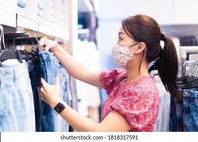 Shopping, Fashion, Style And People During Covid19 - Happy Woman Choosing Clothes Wearing Face Mask In Mall Or Clothing Store.Entrepreneur.Clothes Shop Costume Dress Fashion Store Style Concept.