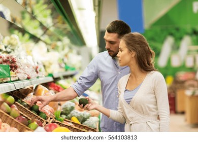 Shopping, Food, Sale, Consumerism And People Concept - Happy Couple Buying Avocado At Grocery Store Or Supermarket