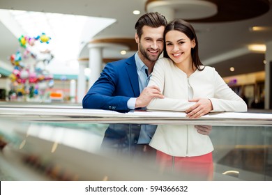 It's Shopping And Fun  Time. Portrait Of Cheerful  Successful Happy Young Lovely Couple Holding  Colored Shopping Bags And Laughing In Mall. Concept Of Consumerism, Sale, Rich Life.