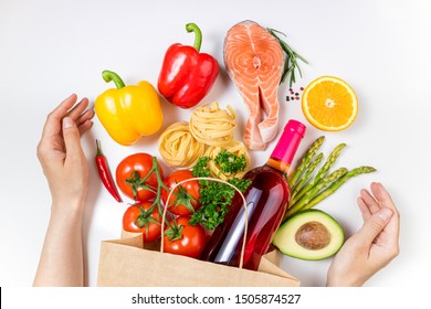 Shopping healthy food and female hands. Healthy food in paper bag fish, pasta, vegetables, fruits and wine on white background. Shopping food supermarket, healthy eating concept. Top view - Shutterstock ID 1505874527