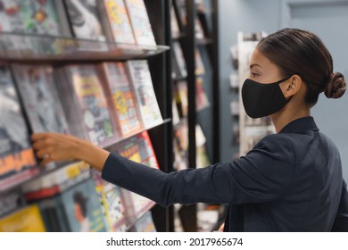 Shopping Indoors During Coronavirus Pandemic. Asian Woman Wearing Face Mask While At Public Library Or Buying Reading Magazine At Newsstand Store In Airport.