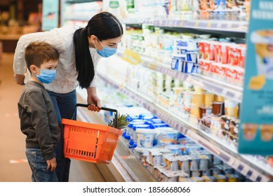 Shopping With Kid During Virus Outbreak. Mother And Child Wearing Surgical Face Mask Buying Fruit In Supermarket. Mom And Little Boy Buy Fresh Vegetable In Grocery Store. Family In Shop.