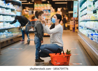 Shopping With Kid During Virus Outbreak. Mother And Child Wearing Surgical Face Mask Buying Fruit In Supermarket. Mom And Little Boy Buy Fresh Vegetable In Grocery Store. Family In Shop.