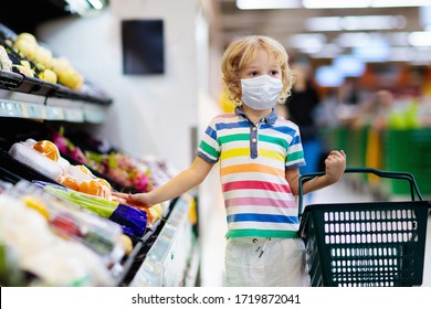 Shopping with kids during virus outbreak. Child wearing surgical face mask buying fruit in supermarket in coronavirus pandemic. Little boy buy fresh vegetable in grocery store. Covid-19 epidemic.