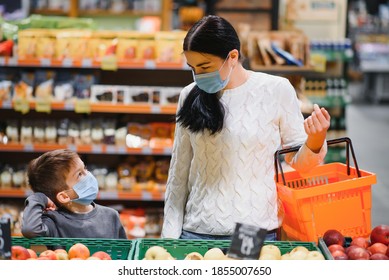 Shopping With Kids During Virus Outbreak. Mother And Child Wearing Surgical Face Mask Buying Fruit In Supermarket. Mom And Little Boy Buy Fresh Vegetable In Grocery Store. Family In Shop.