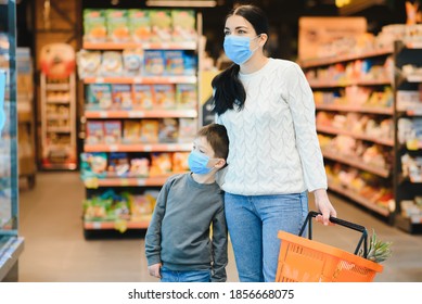 Shopping With Kids During Virus Outbreak. Mother And Child Wearing Surgical Face Mask Buying Fruit In Supermarket. Mom And Little Boy Buy Fresh Vegetable In Grocery Store. Family In Shop.