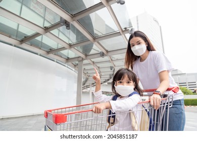 Shopping with kids during a virus outbreak. Asian Mother and daughter wearing surgical face mask going to the supermarket. 