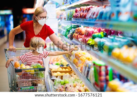 Shopping with kids during virus outbreak. Mother and child wearing surgical face mask buying fruit in supermarket. Mom and little boy buy fresh vegetable in grocery store. Family in shop. 