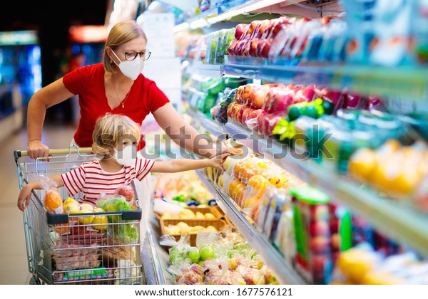 Shopping\
with kids during virus outbreak. Mother and child wearing surgical\
face mask buying fruit in supermarket. Mom and little boy buy fresh\
vegetable in grocery store. Family in shop.\
