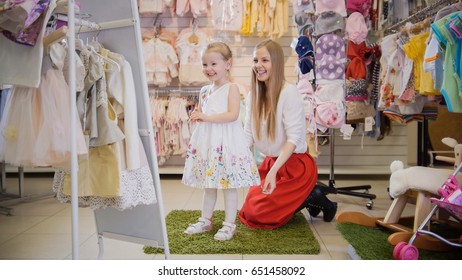 Shopping For Kids. Mom And Daughter Smile In The Mirror