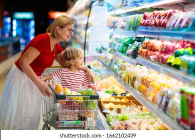 Shopping with kids. Mother and child buying fruit in supermarket. Mom and little boy buy fresh mango in grocery store. Family in shop. Parent and children in a mall choosing vegetables. Healthy food.