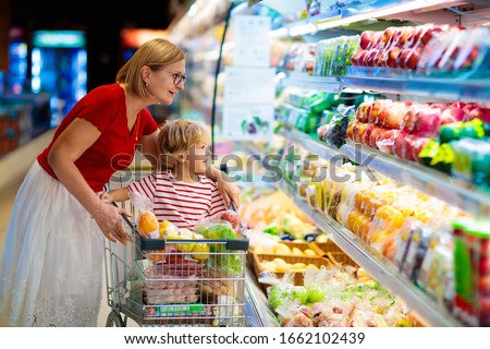 Shopping with kids. Mother and child buying fruit in supermarket. Mom and little boy buy fresh mango in grocery store. Family in shop. Parent and children in a mall choosing vegetables. Healthy food.