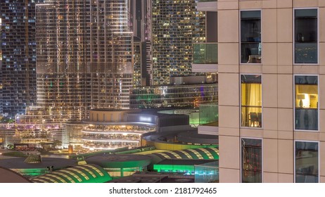 Shopping Mall Exterior During Earth Hour With Reastaurants On Balconies Night Timelapse In Dubai, United Arab Emirates. Aerial Top View With Tallest Skyscraper On A Background. Lights Turning On