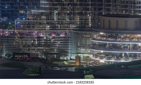 Shopping Mall Exterior With Reastaurants On Balconies Night Timelapse In Dubai, United Arab Emirates. Aerial Top View With Tallest Skyscraper On A Background