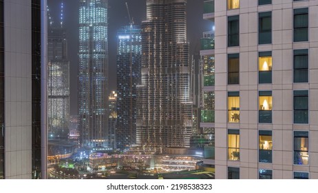 Shopping Mall Exterior With Reastaurants On Balconies Night Timelapse In Dubai, United Arab Emirates. Glowing Windows In Towers. Aerial Top View With Tallest Skyscraper On A Background