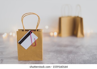 shopping and marketing success conceptual still-life, shopping bag with payment card clipped to it and other bags in the background with fairy lights bokeh - Shutterstock ID 1559160164