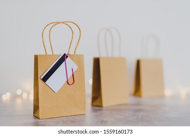 shopping and marketing success conceptual still-life, shopping bag with payment card clipped to it and other bags in the background with fairy lights bokeh - Shutterstock ID 1559160173