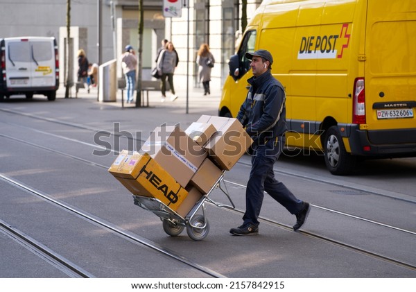 Shopping\
mile Bahnhofstrasse with delivering van of Swiss Post company and\
postman with hand truck full of parcels at City of Zürich. Photo\
taken March 21st, 2022, Zurich,\
Switzerland.