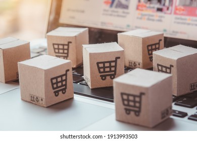 Shopping online. Cardboard box with a shopping cart logo on laptop keyboard. Shopping service on The online web. offers home delivery - Shutterstock ID 1913993503