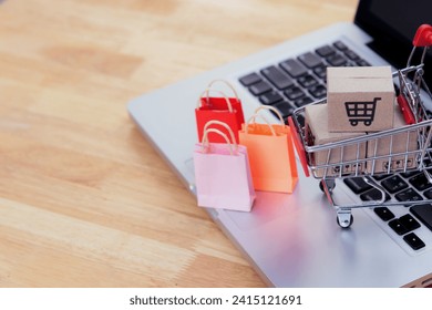 Shopping online. cardboard box with a shopping cart logo in a trolley and paper bag on laptop keyboard. Shopping service on The online web. offers home delivery - Powered by Shutterstock