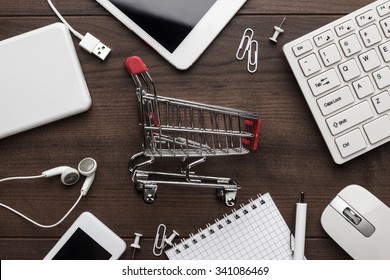 shopping online concept. small red trolley and gadgets on the table