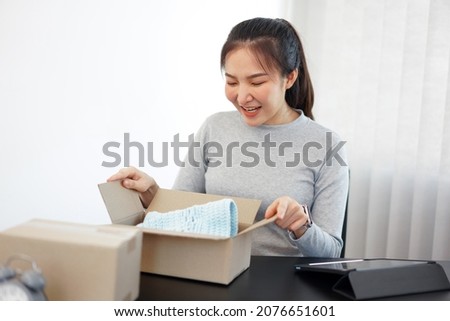 Shopping online concept a smiling woman unboxing an arriving parcel to check the products she bought after waiting with an effort.