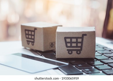 Shopping online. Credit card and cardboard box with a shopping cart logo on laptop keyboard. Shopping service on The online web. offers home delivery - Shutterstock ID 1933065959