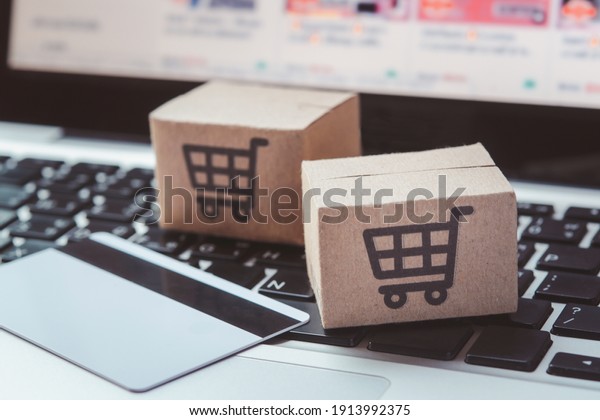 Shopping online. Credit card and cardboard box\
with a shopping cart logo on laptop keyboard. Shopping service on\
The online web. offers home\
delivery