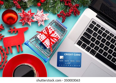 Shopping Online With Credit Card For Christmas Holiday. Laptop With Gifts On Table On Cyan Blue Background