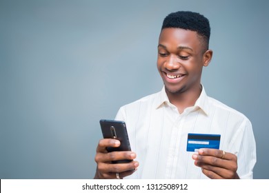 Comprando en línea con su teléfono celular sosteniendo una tarjeta de crédito sonriendo