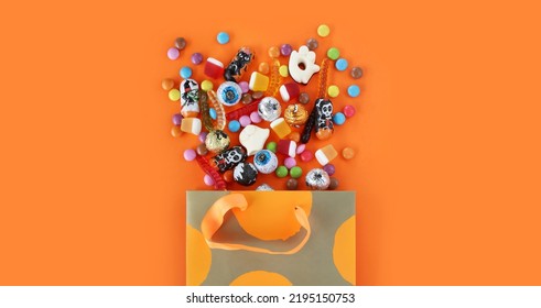 Shopping paper orange polka dot gift bag full of spilled assorted traditional Halloween candies. Orange banner background with copy space. Happy Halloween holiday sale and trick or treat concept. - Powered by Shutterstock