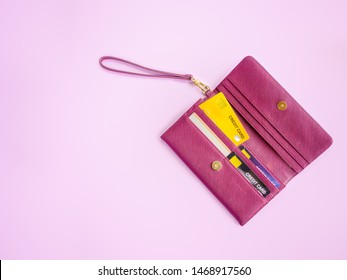 Shopping And Payment Concept From Red Clutch Purse On Pink Background With Credit Cards And Discount Cards In It. Closeup Of Modern Red Leather Wallet. Top View On The Wallet.