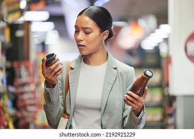 Shopping, retail and customer in a store or supermarket, reading product labels of choice to decide or compare sauce bottles. Consumerism, spending and shopping for food, groceries and a sale offer