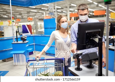 Shopping, Sale, Consumerism And People Concept - Happy Couple In Face Protective Medical Masks For Protection From Virus Disease Buying Food At Supermarket Self-service Cash Register