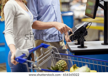 shopping, sale, payment, consumerism and people concept - couple with bank card buying food at grocery store or supermarket self-checkout