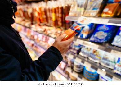 Shopping In Supermarket. Man Check The Shelf Life Of Product In Supermarket. Blurred Photo.