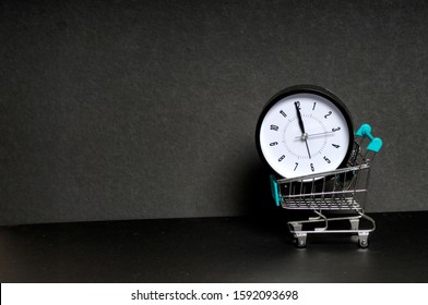 Shopping Time. Alarm clock with trolley cart on black background