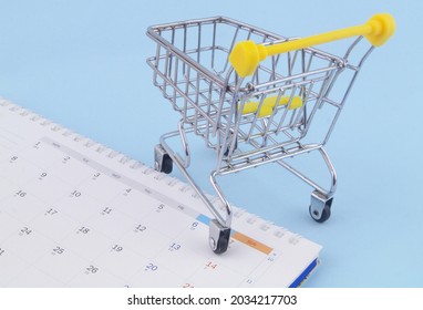 Shopping Trolley With Calendar Close Up. Shopping Time And Sale Days Concept.