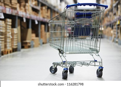 Shopping trolley cart before Rows of shelves with storage boxes in huge warehouse