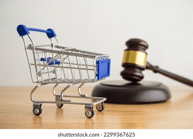 Shopping trolley cart and hammer judge gavel on wooden table with white wall background copy space. Consumer rights and and responsibilities to safety, customer protection, commercial law concept.